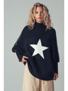 Person wearing a black sweater with a white star design on a plain background