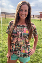 Woman wearing a colorful patterned shirt standing in a grassy field.