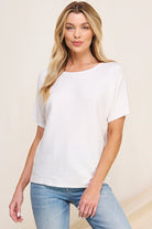 Woman wearing a white t-shirt and light blue jeans against a beige background