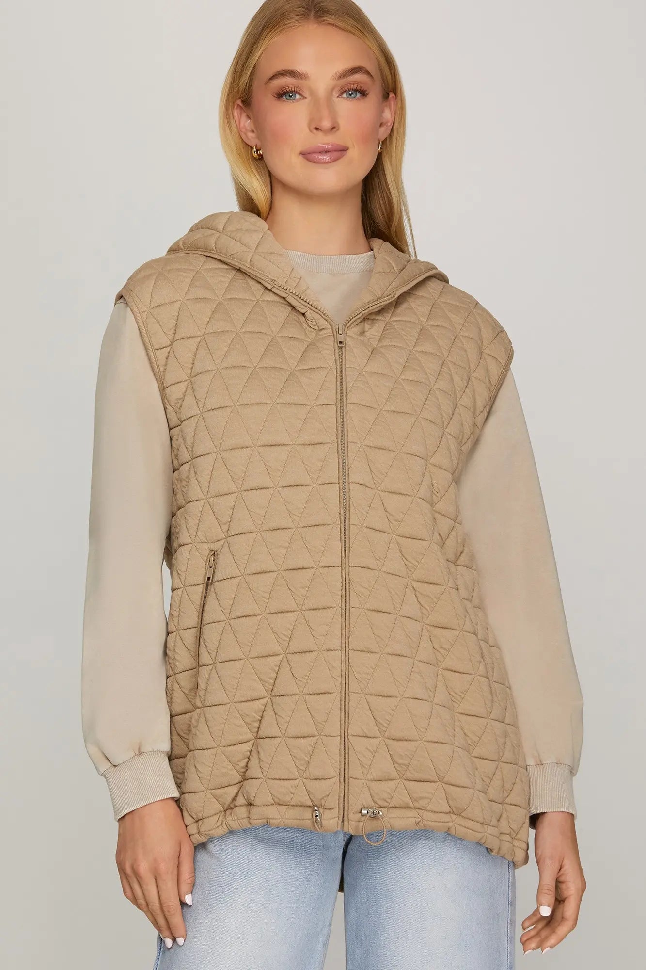 Woman wearing a beige quilted vest zip up oversized fit with zipper pockets
