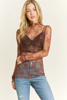 Woman wearing a sheer brown top with lace details on a plain background