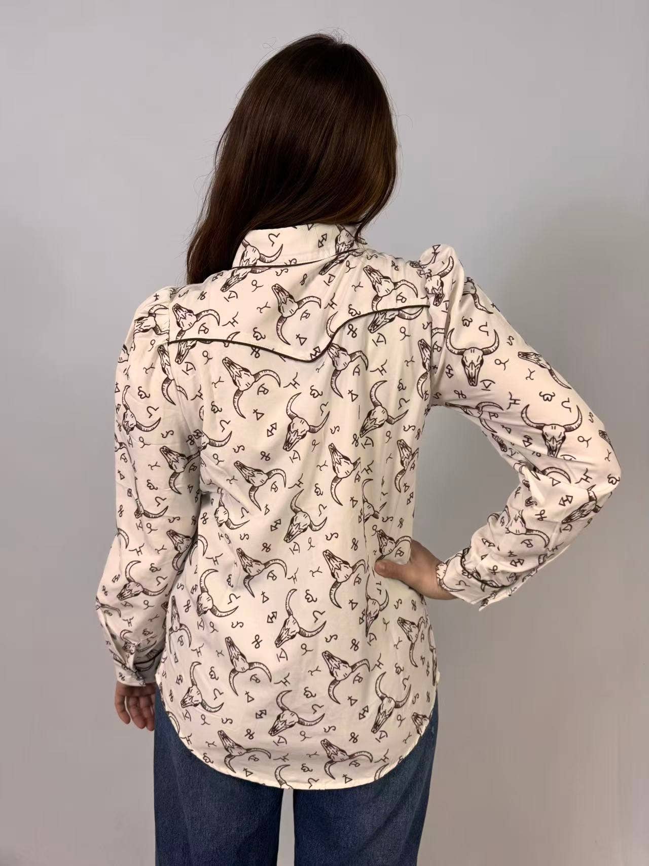 Person wearing a patterned shirt with long sleeves on a gray background