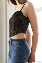 Person wearing a black lace top and blue jeans indoors.