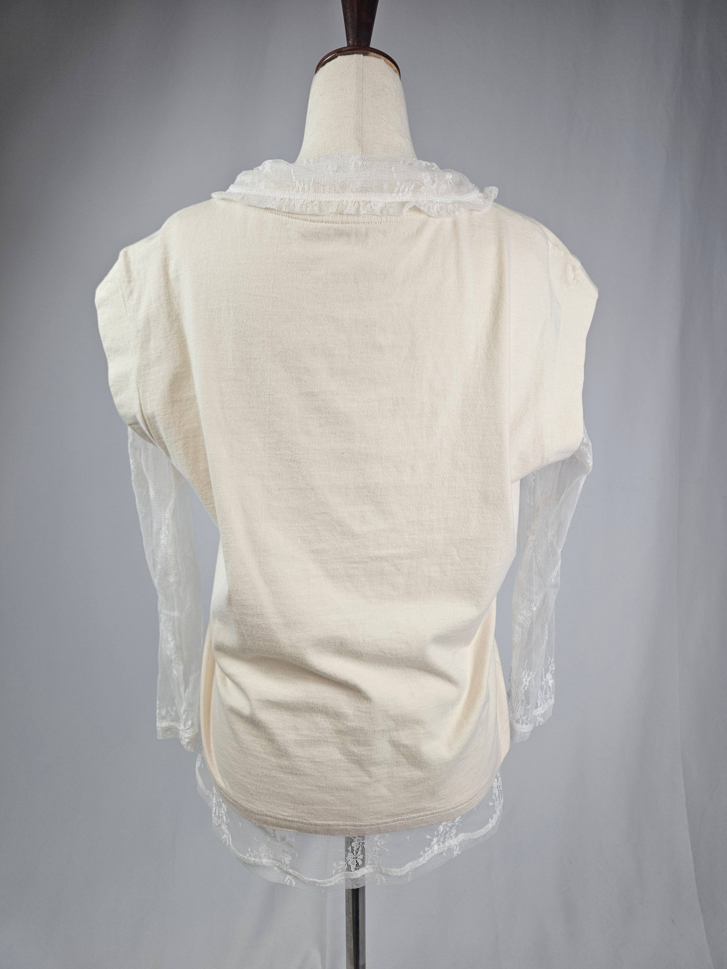 Mannequin wearing a cream-colored top with sheer sleeves and lace details on a gray background