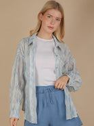 Front view of an oversized sky-blue brushstroke pleated button-down on model, showing drop shoulder, button cuff, and flowing crinkle texture.