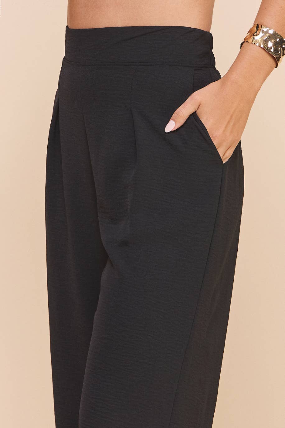 Black wide-leg pants worn by a person on a beige background