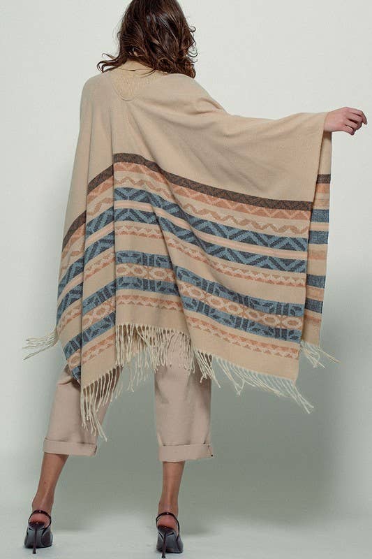 Woman wearing a beige poncho with a  Tan background and light blue, brown, light rust, and grey aztec pattern design  in stripes with tassel trim along bottom hem. Light weight fabric Full back view