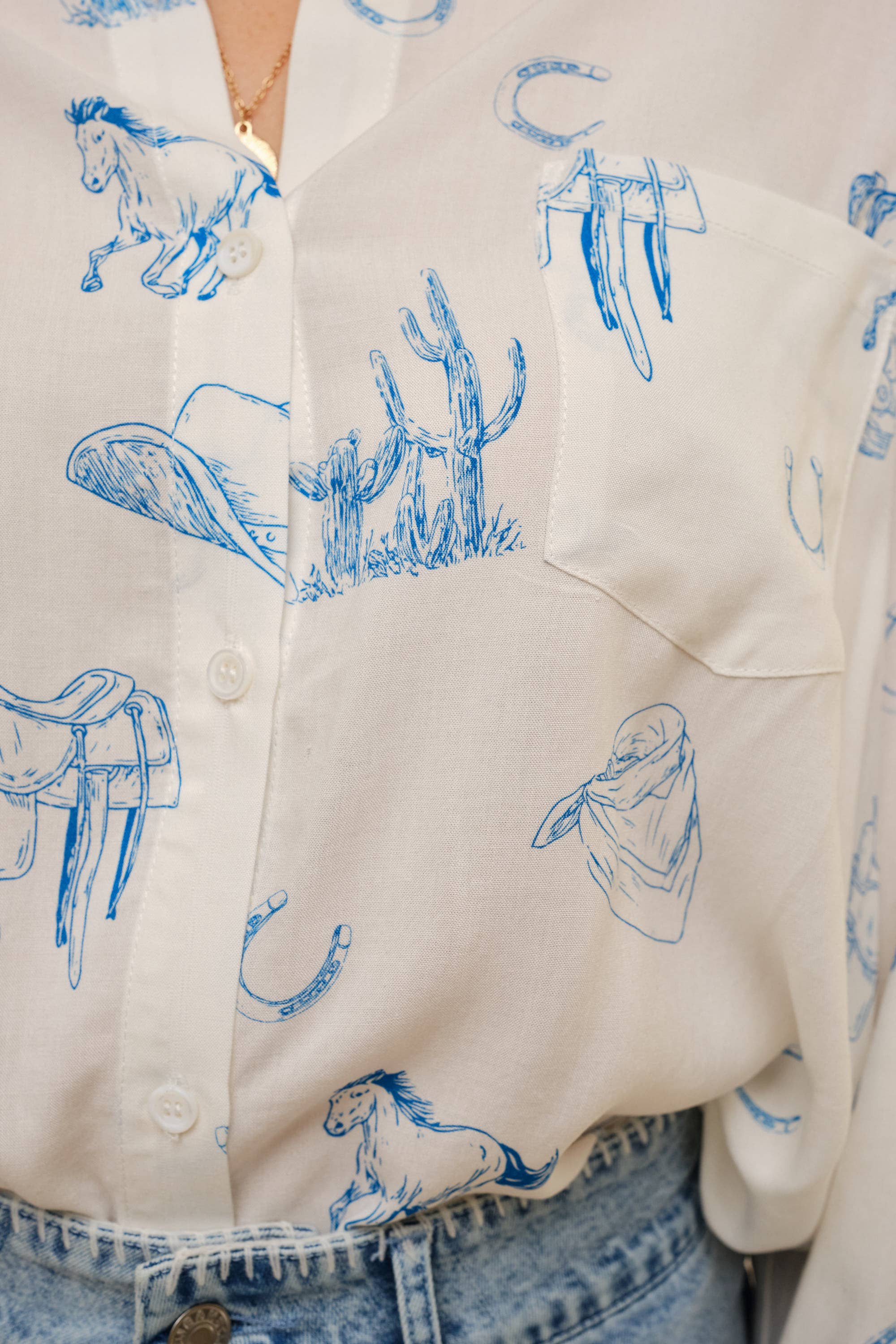 Close-up of a shirt with blue western-themed illustrations on a beige background