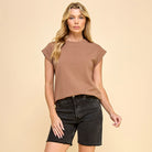 Woman wearing a brown t-shirt and black shorts on a beige background