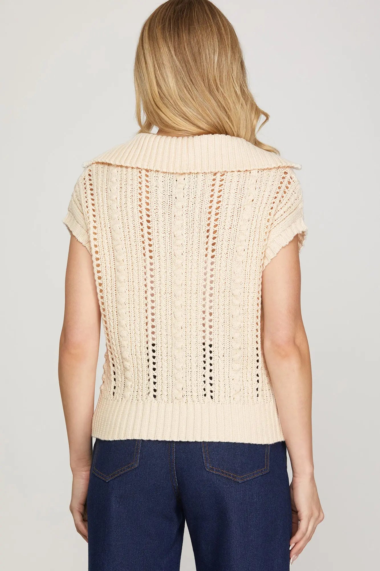 Back view of Woman wearing a beige knitted vest top short sleeve 