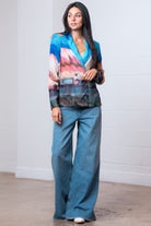 Woman wearing a colorful blazer and blue pants against a white background