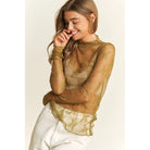 Woman wearing a sheer olive top with lace details on a plain background