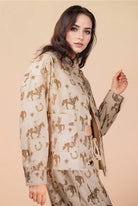 Woman wearing a beige outfit with horse pattern on a beige background