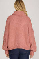Back view of rosy-rust cable knit turtleneck sweater with ribbed cuffs and hem.