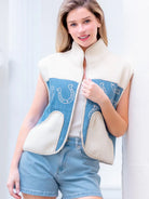 Model wearing indigo denim vest with white horseshoe print and faux-fur collar, zipped front, hands in pockets.”