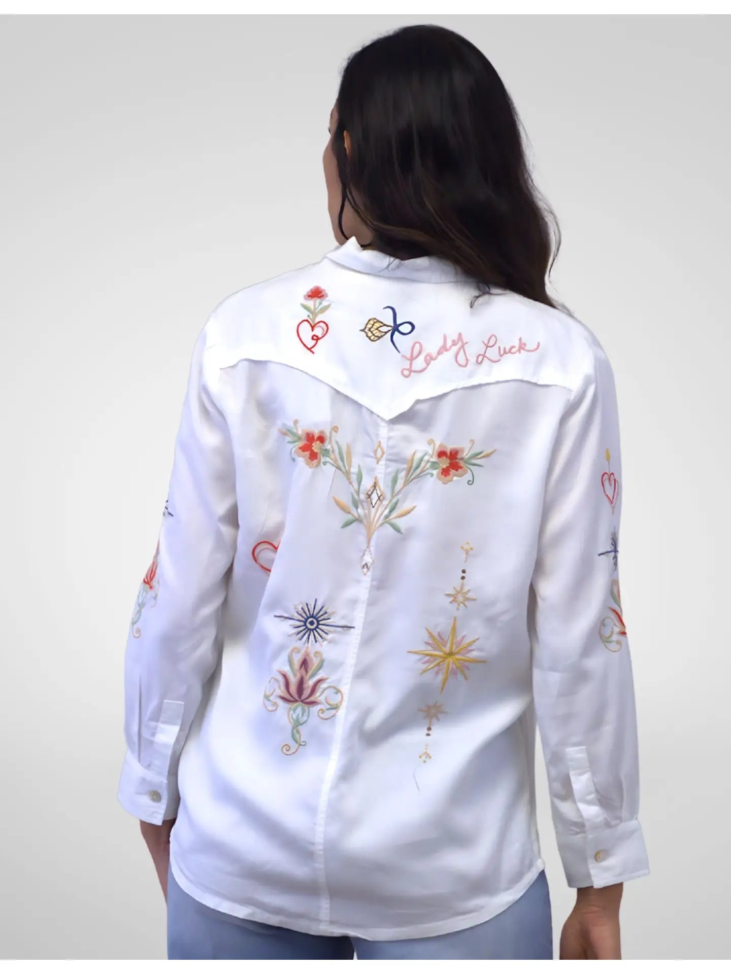 White embroidered shirt worn by a person on a plain background