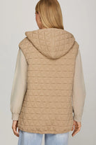 Back View Woman wearing a beige quilted vest zip up oversized fit with zipper pockets