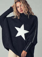 Woman wearing a black sweater with a white star design on a gray background