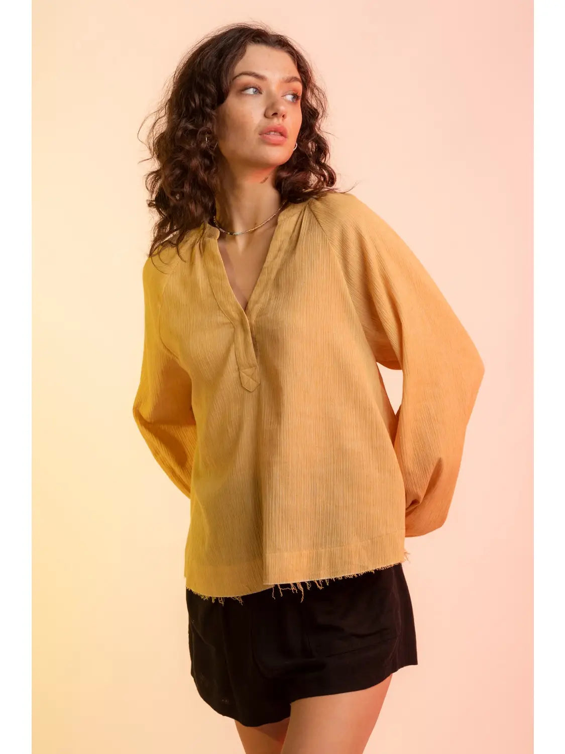 Model wearing yellow gauze V-neck blouse with raglan bubble sleeves and raw hem, 
