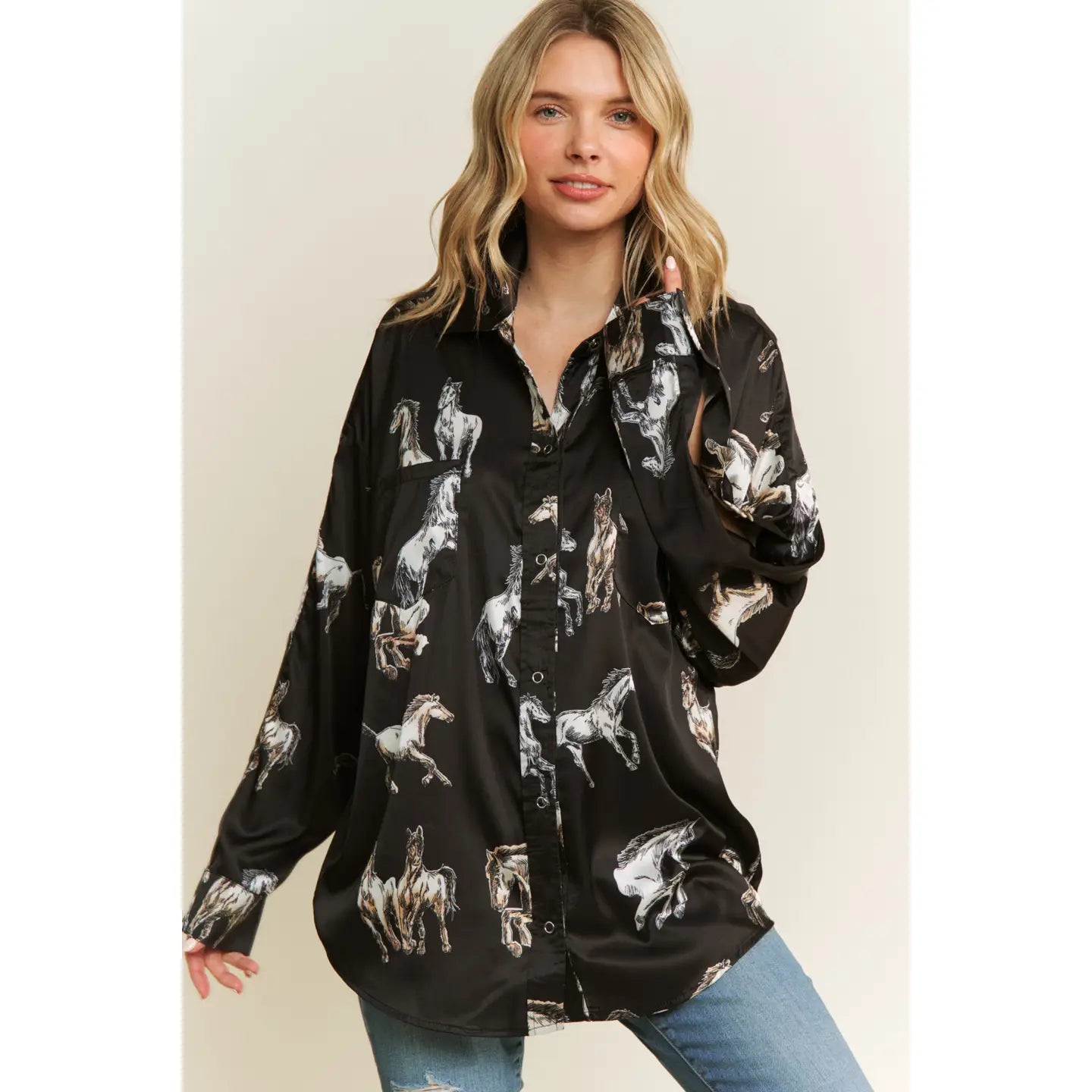 Woman wearing a black button-up shirt with horse print against a beige background