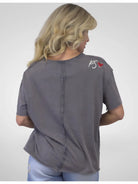 Person wearing a gray shirt with a logo on the back against a white background