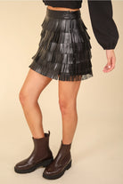 Side profile of black vegan leather fringe mini skirt demonstrating swingy tiers.