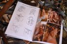 Open book with sketches and photographs of hairstyles on a textured surface.