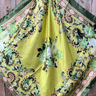 Yellow fabric with intricate green and black patterns on a wooden surface