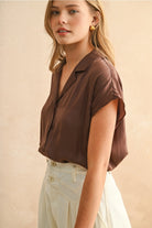 Woman wearing a brown blouse against a beige background