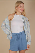 Front  view of an oversized sky-blue brushstroke pleated button-down on model, showing drop shoulder, button cuff, and flowing crinkle texture.