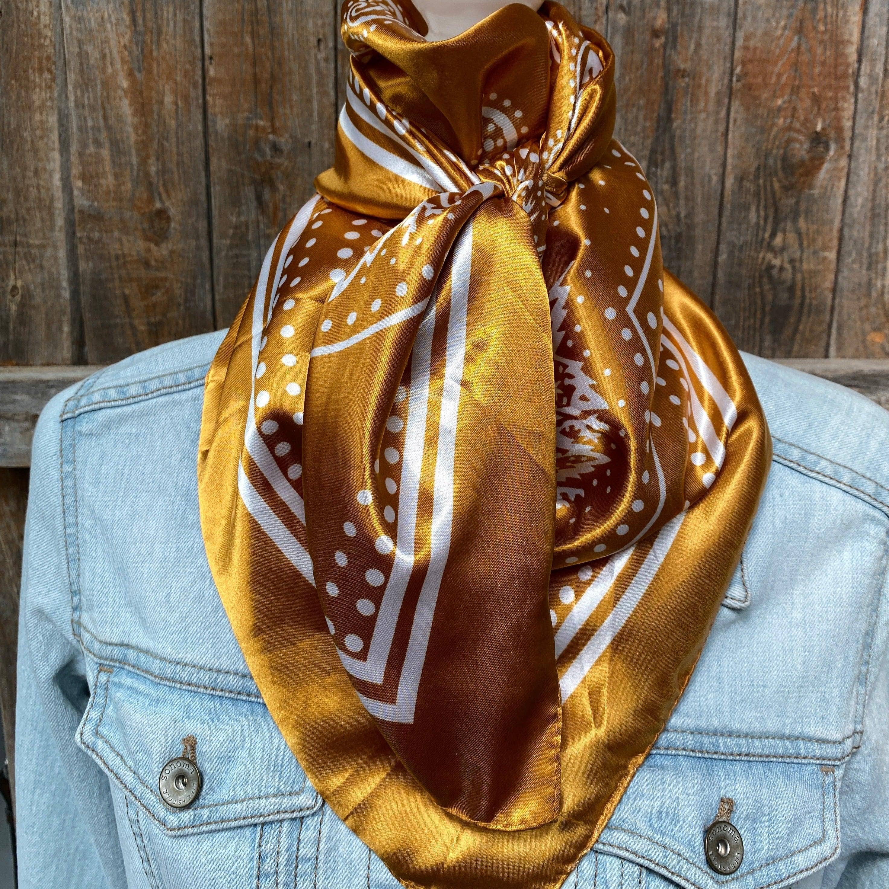 Mustard yellow  patterned scarf draped over a denim jacket against a wooden background