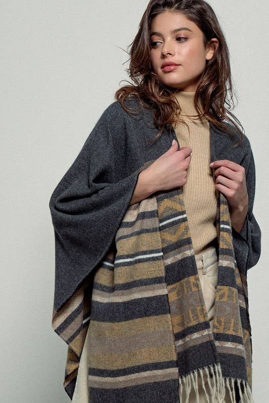 Dark gray poncho with brown and beige striped pattern and fringes on a white background