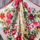 Floral patterned fabric scarf with red, yellow, and green flowers on a wooden surface