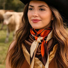 Woman wearing a colorful scarf and cowboy hat with cows in the background