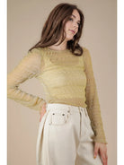 Front view: Model wearing champagne sheer lurex long-sleeve fitted top with crew/mock neck; subtle sparkle visible.