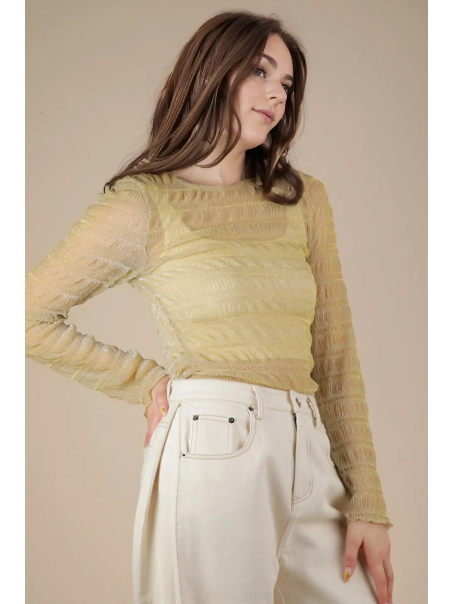Front view: Model wearing champagne sheer lurex long-sleeve fitted top with crew/mock neck; subtle sparkle visible.