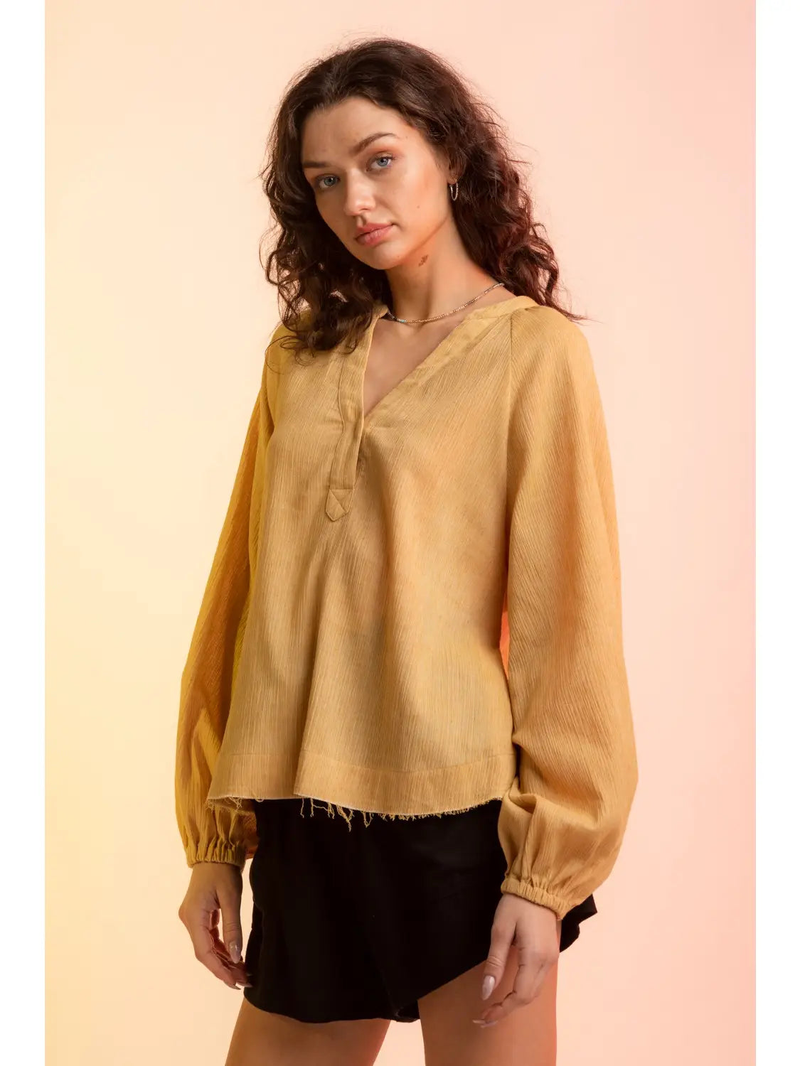 Model wearing yellow gauze V-neck blouse with raglan bubble sleeves and raw hem, 