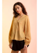 Model wearing yellow gauze V-neck blouse with raglan bubble sleeves and raw hem, 