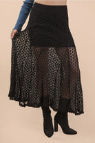 Black lace skirt worn by a person on a beige background