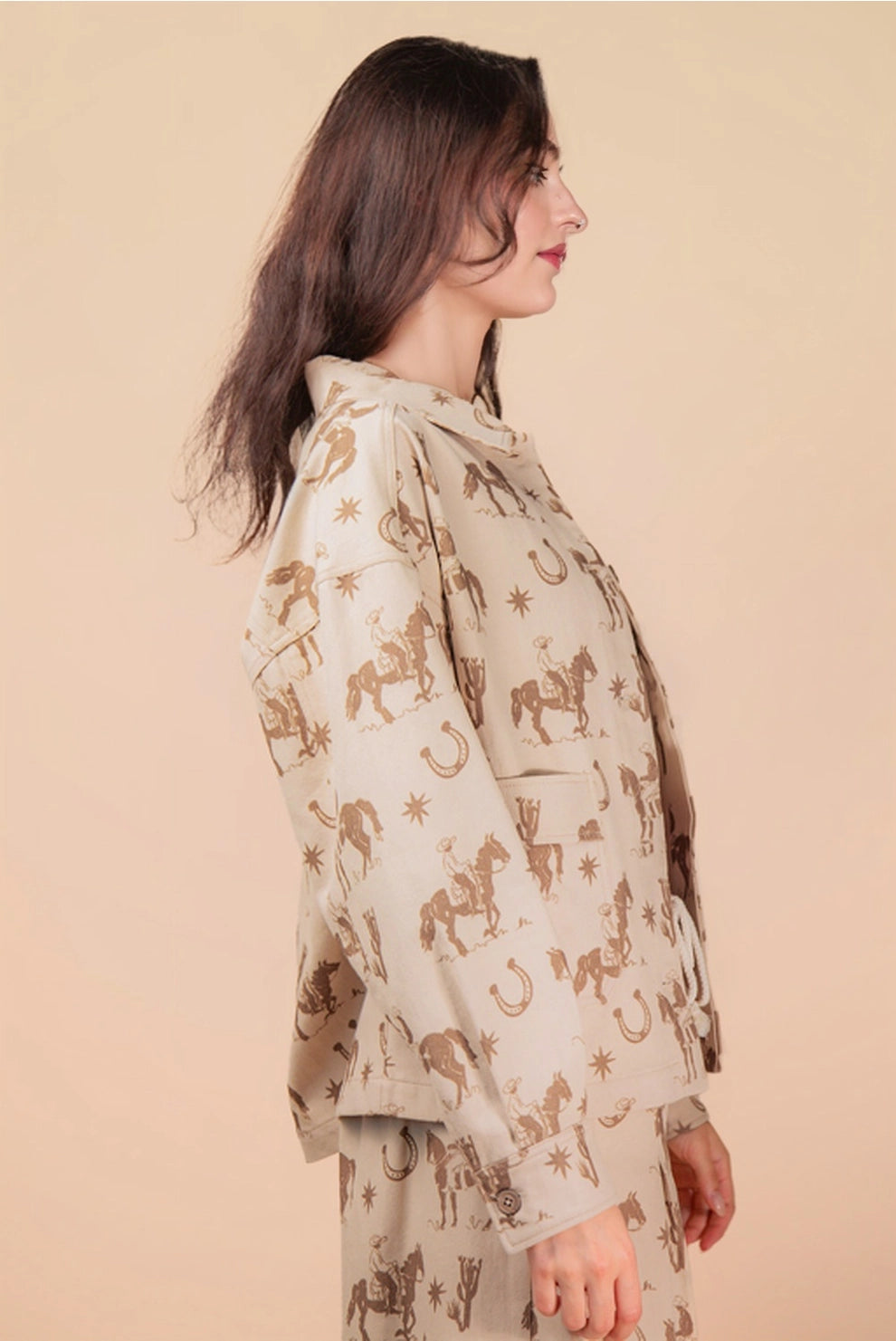 Woman wearing a beige outfit with horse pattern on a beige background