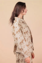 Woman wearing a beige outfit with horse pattern on a beige background