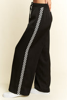 Black pants with white checkered stripes on a beige background