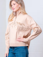 Taupe high-neck quarter-zip sweater with horse embroidery on model, front view.