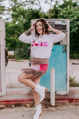 Woman posing in front of a vintage gas pump wearing a 'Girl' sweatshirt.