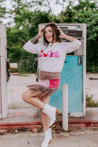 Woman posing in front of a vintage gas pump wearing a 'Girl' sweatshirt.