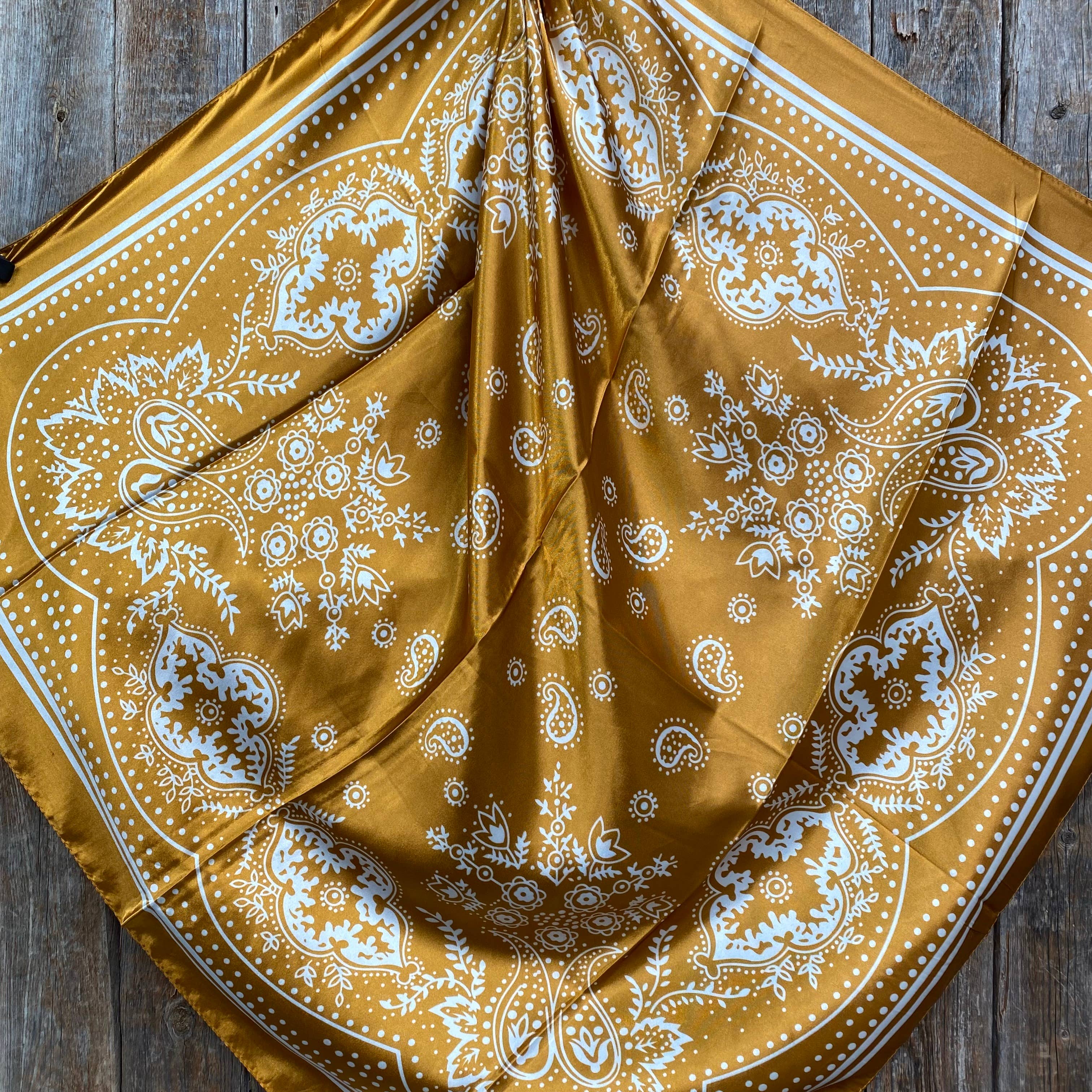 Yellow mustard bandana with white paisley patterns on a wooden surface