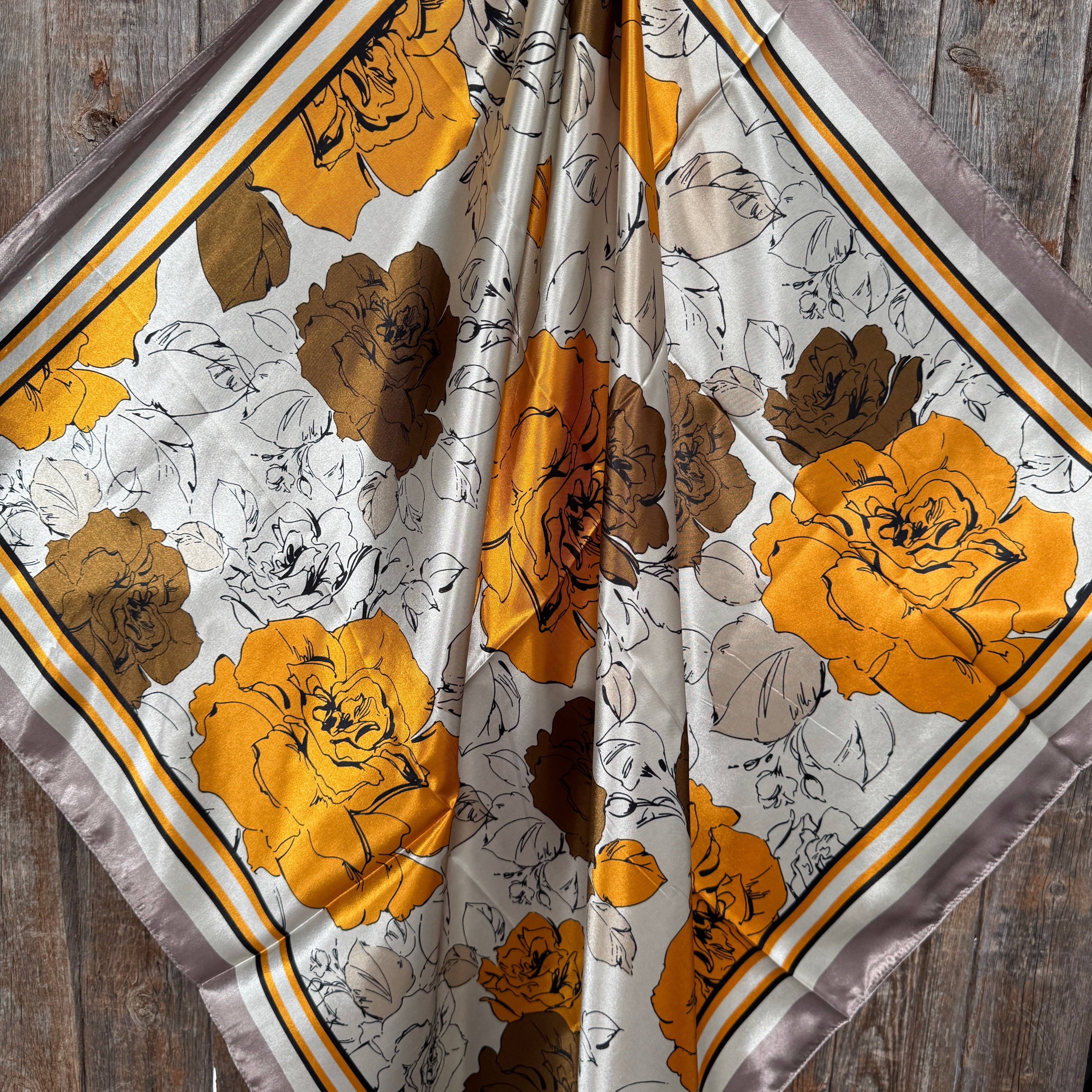 Floral patterned fabric with yellow, brown, and white flowers on a wooden background