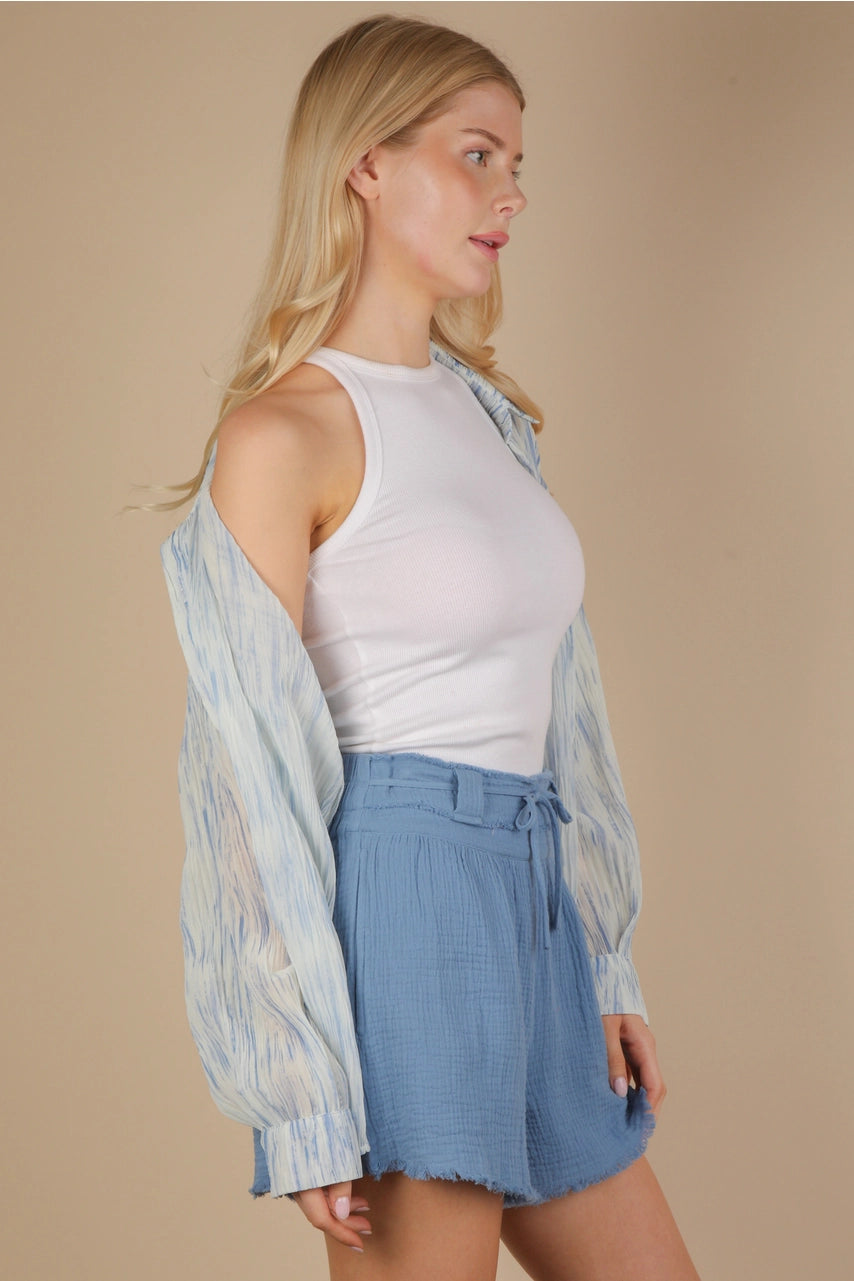 Side view of an oversized sky-blue brushstroke pleated button-down on model, showing drop shoulder, button cuff, and flowing crinkle texture.