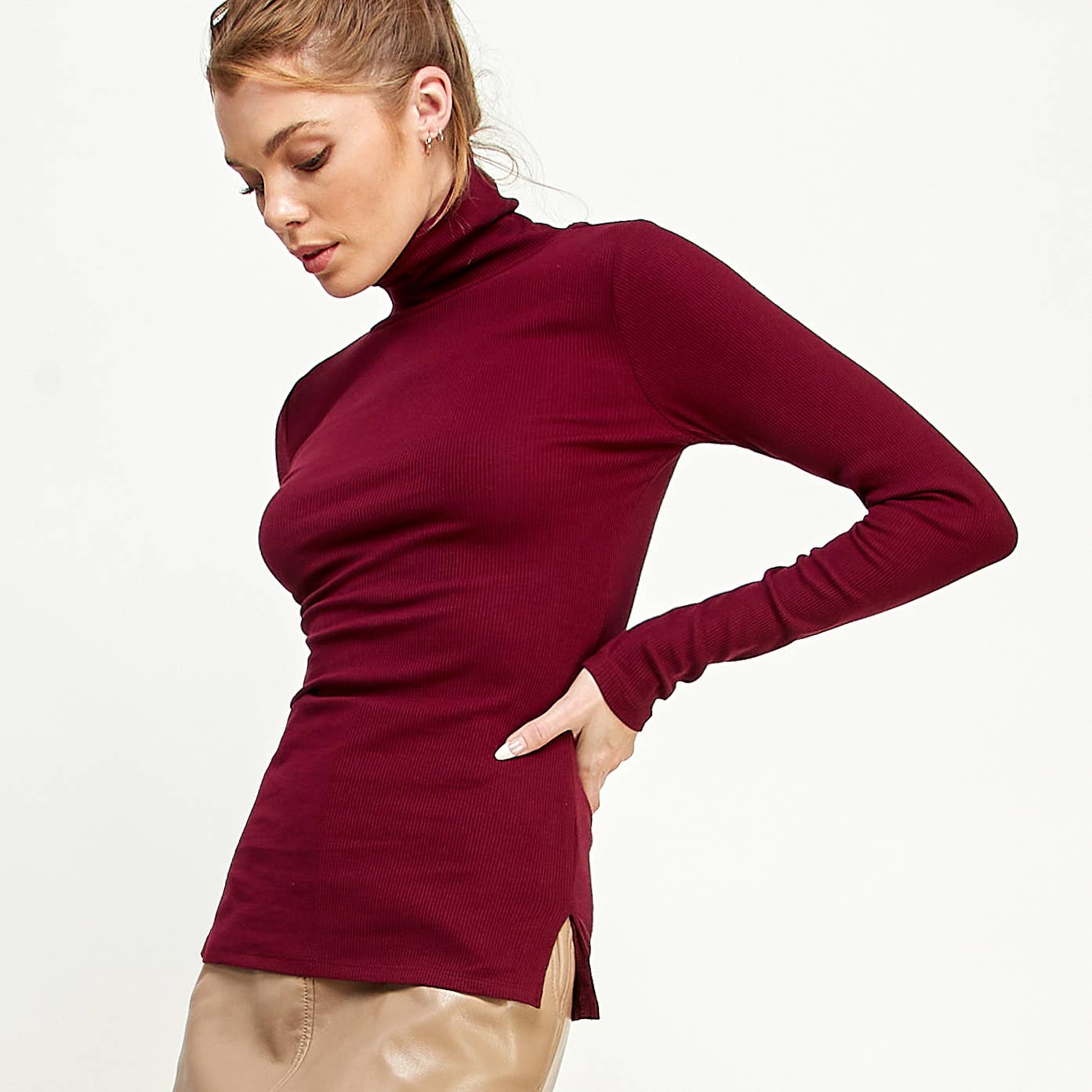 Woman wearing a burgundy turtleneck sweater on a white background