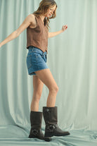 A woman wearing a camel suede snap-up vest over a white shirt, paired with Denim Shorts